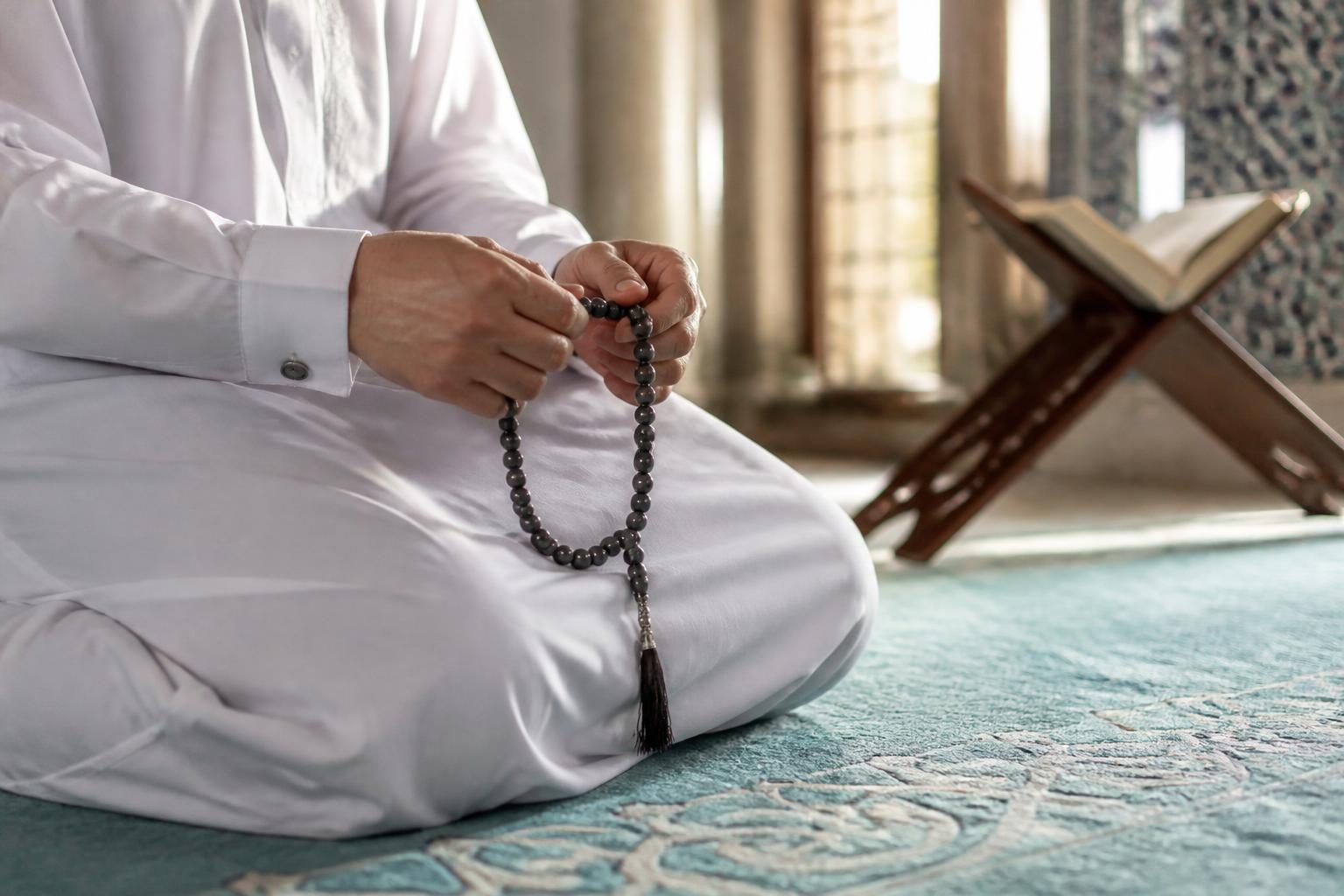 Namaz sonrası tesbihat yapan kişi, seccade üzerinde tespih çekiyor